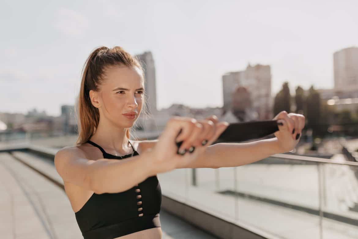 sporty-woman-stretching-her-arms-looking-concentrated-outdoor-city